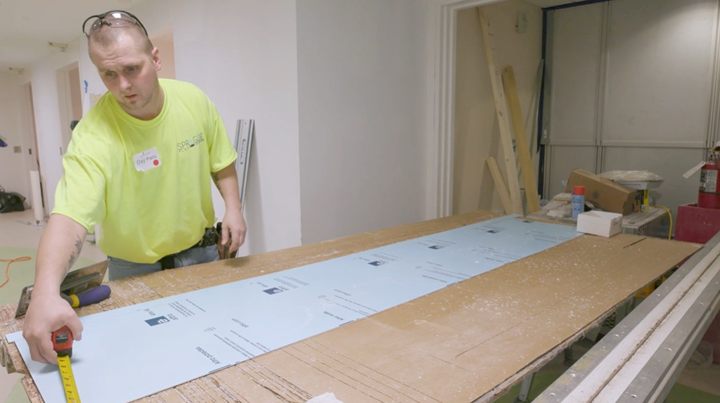 A worker from Sprague Floor Covering measures
